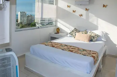 a white bedroom with a bed and a window at Vista al Mar - 77Rentals in Cartagena de Indias