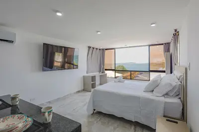 a white bedroom with a bed and a large window at Lujoso apartamento con vista al mar in Cartagena de Indias
