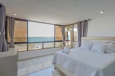a bedroom with a white bed with a view of the ocean at Lujoso apartamento con vista al mar in Cartagena de Indias