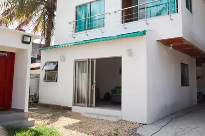 a white house with a red door and a palm tree at Apartamento Villa Carolina 101 in San Antero