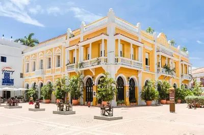a large yellow building with trees in front of it at Casa en la mejor plaza de la ciudad vieja in Cartagena de Indias