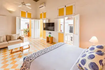 a bedroom with a large bed and a living room at Casa en la mejor plaza de la ciudad vieja in Cartagena de Indias