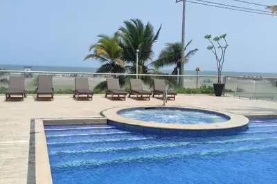 a swimming pool with chairs and the ocean in the background at Apartamento en Cartagena de Indias, Edificio Morros 3 in Cartagena de Indias