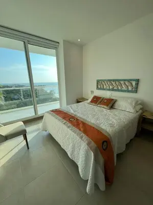 a bedroom with a large bed and a large window at Edificio Playa dormida 2 con Piscina y playa in Santa Marta
