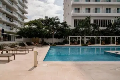 a swimming pool with chairs and a building at Edificio Playa dormida 2 con Piscina y playa in Santa Marta