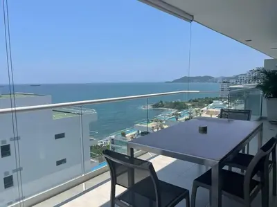 a table and chairs on a balcony with a view of the ocean at Edificio Playa dormida 2 con Piscina y playa in Santa Marta