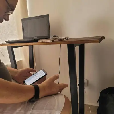 a person holding a remote control under a table with a laptop at la Ola de la Vida con AA WIFI in Cartagena de Indias