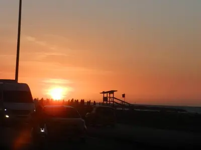 a sunset at the beach with cars parked in a parking lot at la Ola de la Vida con AA WIFI in Cartagena de Indias