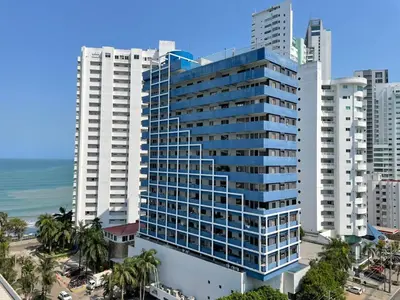 a tall building with palm trees in front of a city at Portofino Cartagena Bocagrande 604 ICDI in Cartagena de Indias