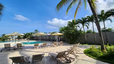 a pool with chairs and umbrellas and palm trees at Sensacional! Apartamento Cartagena Morros SeaWay in Cartagena de Indias