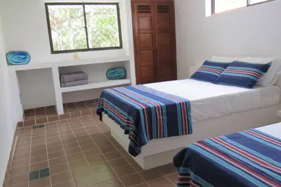 a bedroom with two beds and a window at Casa Amin Tolu in San Silvestre