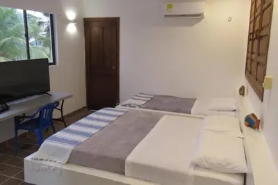 two beds in a room with a desk and a television at Casa Amin Tolu in San Silvestre