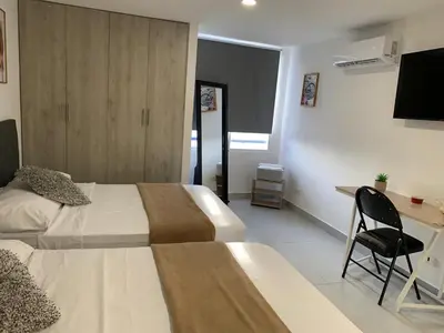 a hotel room with two beds and a desk at Apartamento bonito en Cartagena ,el laguito bocagrande con vista al mar in Cartagena de Indias