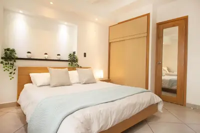 a bedroom with a large white bed and a mirror at Riviera Sunrise Beach - Frente al mar y vista panorámica a toda la ciudad in Cartagena de Indias