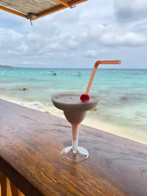 a drink sitting on a table in front of the ocean at Itaca Eco House in Playa Blanca