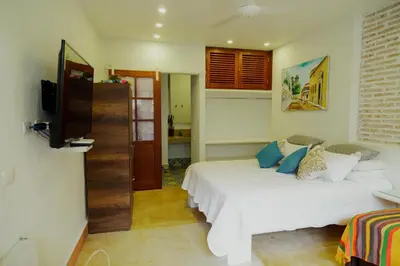 a bedroom with a white bed with blue pillows at Spiritual Luxury 4BR Pool&Roofterrac Getsemani NEW in Cartagena de Indias