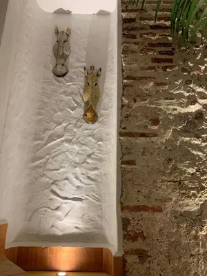 two metal masks on a wall next to a stone wall at Spiritual Luxury 4BR Pool&Roofterrac Getsemani NEW in Cartagena de Indias