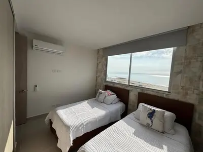 two beds in a room with a large window at Cartagena SUNNO BEACH in Cartagena de Indias