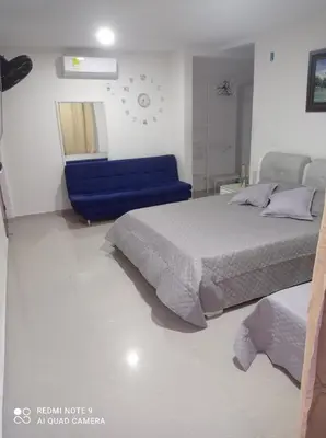 a bedroom with a bed and a blue couch at Cabaña campestre Villa Liliana in Juan de Acosta
