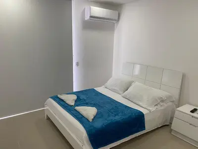 a white bedroom with a bed with a blue blanket at Apartamento 414 en Ocean Drive - Crespo Cerca al Mar in Cartagena de Indias