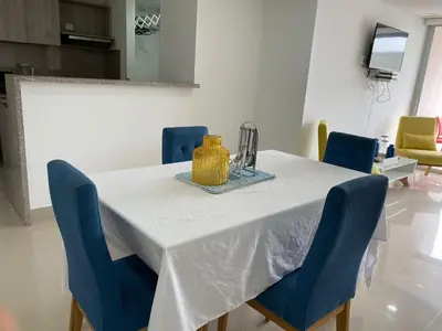 a dining room table with blue chairs and a white table cloth at Apartamento 414 en Ocean Drive - Crespo Cerca al Mar in Cartagena de Indias