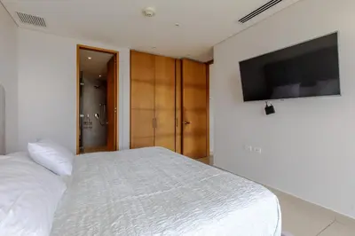 a bedroom with a white bed and a flat screen tv at Apartamentos en Edificio H2 Bocagrande Cerca al Mar in Cartagena de Indias