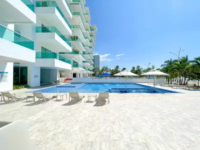 a swimming pool with chairs and umbrellas next to a building at Magico Apartaemento Frente al Mar 4 Habitaciones E92 in Coveñas