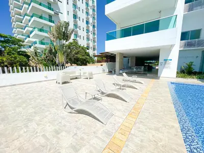 a group of white chairs and a pool in a building at Magico Apartaemento Frente al Mar 4 Habitaciones E92 in Coveñas