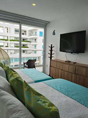 a bedroom with two beds and a flat screen tv at Apartamento con salida privada a la playa en Morros, Cartagena in Cartagena de Indias