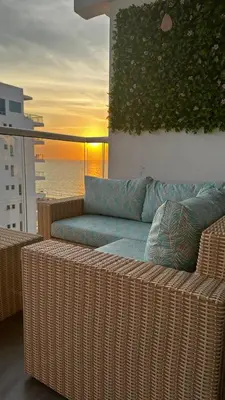 a wicker couch sitting on a balcony with the sunset at Apartamento con salida privada a la playa en Morros, Cartagena in Cartagena de Indias