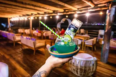 a person holding a drink in a bowl with a bottle at Palmarito Beach Hotel in Tierra Bomba