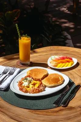 a table with two plates of breakfast food and a glass of orange juice at Pao Pao Cartagena in Isla Grande