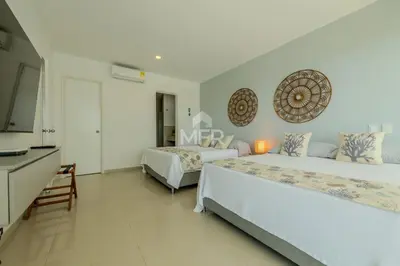 a bedroom with two beds and a television in it at Morros Epic Beachfront Apartment in Cartagena de Indias