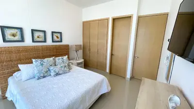 a bedroom with a white bed with blue pillows at Magico Apartamento Frente al Mar 4 Habitaciones BM63 in Coveñas
