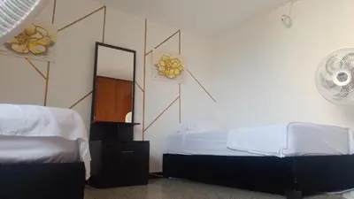 a bedroom with two beds and a mirror on the wall at Confortable habitación en apartamento familiar en el Prado in Barranquilla