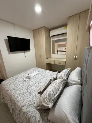a bedroom with a bed with pillows and a tv at Apartaestudio Amoblado Tipo Loft en Barrio la Campiña in Cartagena de Indias