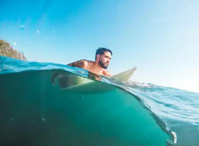 a man laying on a surfboard in the water at Hermoso Apartamento cerca a la playa in Cartagena de Indias
