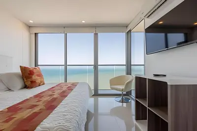a bedroom with a bed and a desk and some windows at Awesome Oceanfront “Morros City” 29th floor 2R/3BR in Cartagena de Indias