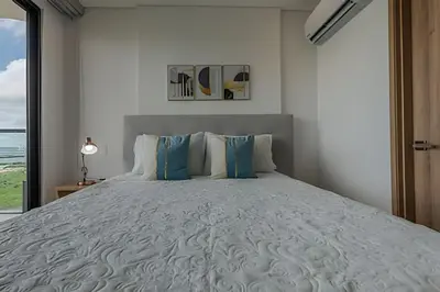 a bedroom with a large white bed with blue pillows at Awesome View Historic Center, Castle and Sea 2BR in Cartagena de Indias
