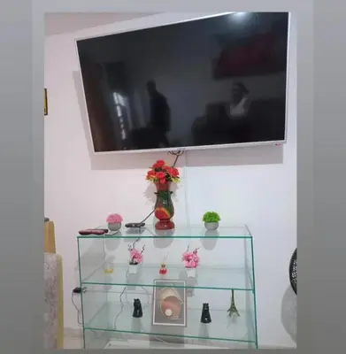 a glass shelf with flowers and a tv on a wall at Casa rosymar in Cartagena de Indias