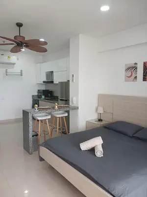 a bedroom with a bed and a kitchen with stools at Cartagena Beach Resort cerca al aereopuerto in Cartagena de Indias