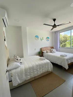 a bedroom with two beds and a window at Hotel Aqua House in Tubará