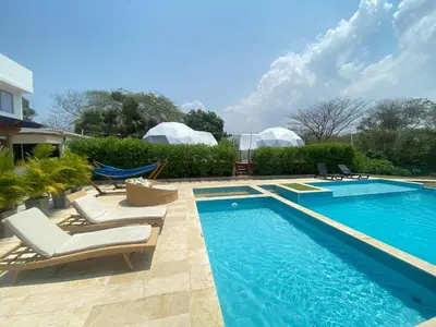 a swimming pool with chaise lounge chairs next to a house at Hotel Aqua House in Tubará