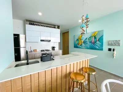 a kitchen with a sink and a counter with stools at Magico Apartamento Frente al Mar 3 Habitaciones TR22 in Coveñas