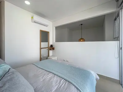 a white bedroom with a bed and a mirror at Bocagrande Loft - Livin Colombia in Cartagena de Indias