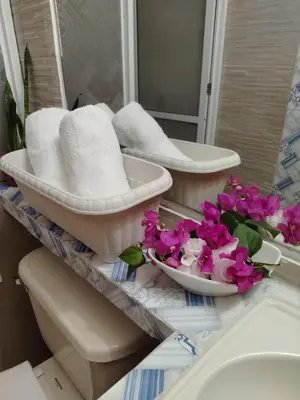a bathroom with two sinks and towels and flowers at Hostal CORALES in Tolú