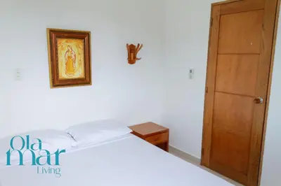 a bedroom with a white bed and a wooden door at Atardeceres bloque A in Coveñas