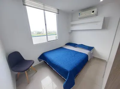 a small bedroom with a blue bed and a chair at Apartamento Cartagena - Terrazas de Calicanto in Cartagena de Indias