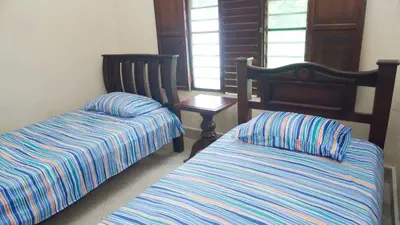 a bedroom with two beds and a table and window at Cabaña Villa Palmaral in Moñitos