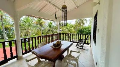a dining room with a table and chairs on a balcony at Cabaña Villa Palmaral in Moñitos